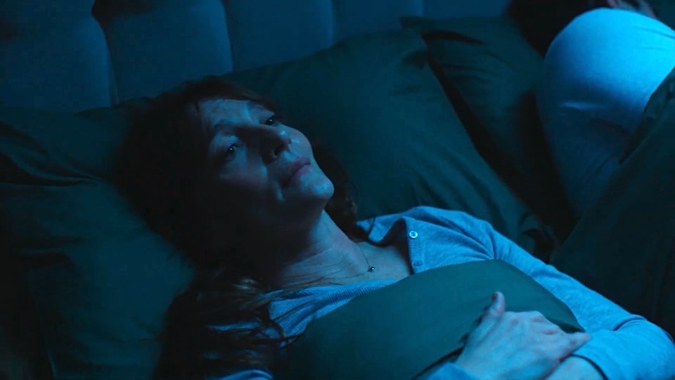 care 2 | Muse by Clios Person lying in bed under blue-tinted light, hands resting on chest.