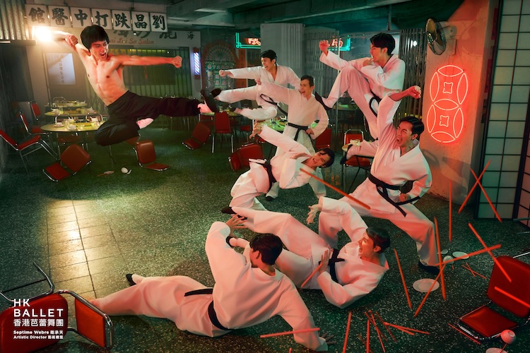 Group of martial artists in white gis with black belts perform high kicks in a neon-lit training space.