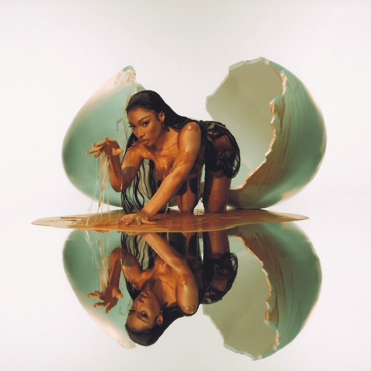 MEGAN Megan Thee Stallion | Muse by Clios Woman in a dark outfit crawls out from two large cracked eggshells on a glossy, reflective surface, creating a mirrored image with liquid accents.