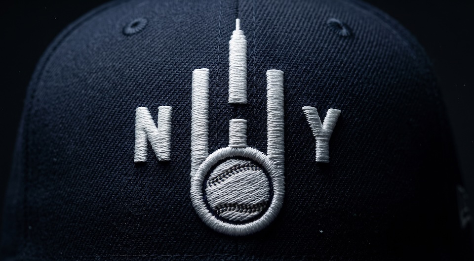 Close-up of a dark navy cap with white embroidered'N Y' and a circular skyline/basketball design symbolizing New York.