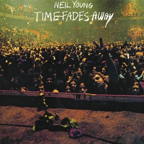 Crowd of concertgoers in a packed arena with hands raised toward the stage; 'Neil Young Time Fades Away' text appears at the top.