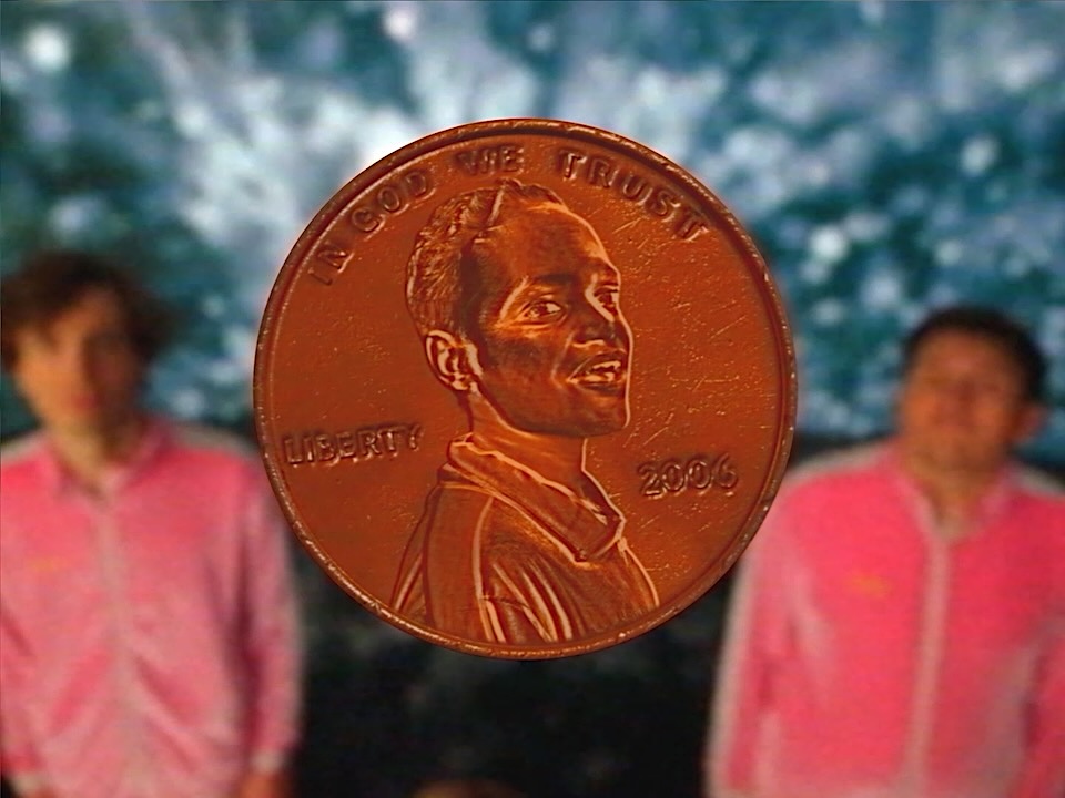 Close-up of a copper penny featuring Lincoln's profile, 2006, with 'In God We Trust' and 'Liberty' visible; blurred figures in pink shirts in the background.